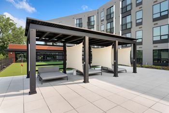 a patio with a pergola and lounge chairs